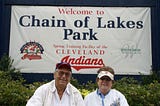 2 people sitting in front of a Cleveland Indians sign