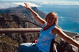 Kathy in her all-terrain wheelchair with arms outstretched on top of Table Mountain in South Africa