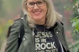 Photo of woman smiling and wearing a shirt that says, “Jesus is my Rock”