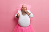 Rotund bearded giggly man wearing a tutu, tiara and tiny wings