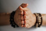 Woman’s hands with palms together practicing meditation or praying indoors.