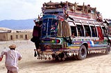 Man chasing a colorful bus in Afgh