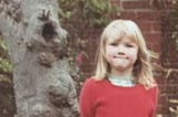 The author as a child, wearing a red woolen jumper.