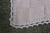 A pink crochet blanket worked in a textured basketweave stitch