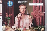 An Edinburgh Fringe poster showing a red-headed white man holding a wine-glass and an apothecary’s bottle. There’s a cross to his left, roses to his right and a mess on the table in front of him, including a pineapple, a human skull, grapes and a female bust.