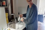 Tamsen smiling at kitchen sink as she arranges fresh flowers in a vase