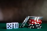 2 dice — one showing a five and one showing a six — next to a stack of multicoloured gambling chips