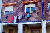 A loaded line of laundry hangs from a second story window.