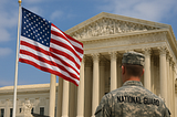 An anonymous National Guardsman gazing up at the U.S. flag and the Supreme Court building