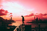 Man standing on edge of building in Hong Kong.