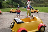 Models of the Enid Blyton characters Noddy and Big Ears, standing in the middle of a ring of model Noddy cars.