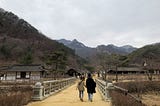 Mungyeong Saejae stone bridge that leads hikers through a traditional Korean village with the mountains of Korea in the distance.