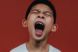 A young boy with his mouth wide open screaming, on a red background, Nyk, Medium