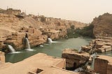 An image of an ancient hydraulic water system in Shushtar, Iran. The picture shows stone constructions with water flowing into a central dam.