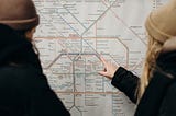 Two people view a transit map to plan out a route.