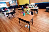 Children in a pre-school class wear masks and sit at desks spaced apart as per coronavirus guidelines during summer school.