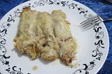 Three chicken-filled savory crepes, smothered in white sauce and cheese.