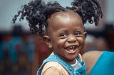 A child smiling at the camera. You can see all five of her milk teeth.