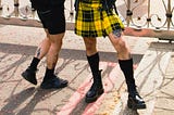 Man in a yellow plaid skirt with black knee socks and combat boots