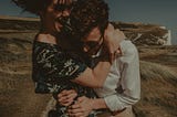 A happy couple embraces in a grassy field