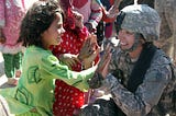 An Afghan girl greets an American female soldier.