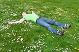 Person lying on back in a field of flowers