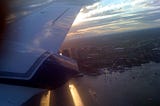 A small 10-seater plane overlooking Boston Logan Airport at sunset.