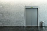 The closed door of an elevator against a grey wall