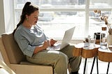 Woman sitting on a sofa while using a laptop.