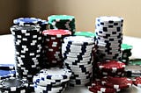Photograph of stacks of varying heights of white, black, red, green, and blue poker chips.