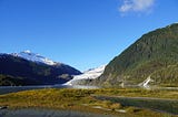 Scenic photo of Mendenhall Glacier in Juneau Alaska, nestled between mountains in a late Alaskan summer