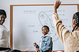 Black children are in a classroom with a Black teacher.