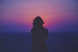 A woman’s silhouette against the sunset. Photo by Sasha Freemind on Unsplash