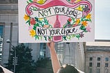 A woman holds a sign reading, “not your body, not your choice” at a political protest for abortion rights.