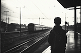 Black and white photo of boy watching trains