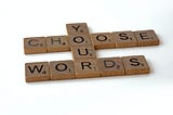A photo of scrabble tiles forming the phrase — Choose your words