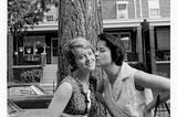 A woman kissing her sister in front of a tree in Bethesda, MD