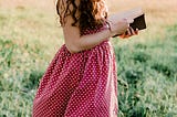 A Girl in the field reading a book