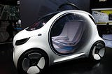 A futuristic small white car with a circular door that is transparent, looking like it’s made out of glass with two seats inside.