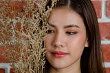 close-up-young-beautiful-attractive-asian-female-model-s-face-with-flower-s-branch-against-orange-brick-wall-background — Un Swede