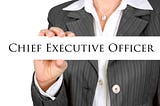 A woman wearing a suit holding a sign that says “Chief Executive Officer.”