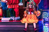 a girl in clown makeup holding a balloon