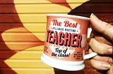 A hand holding a best teacher mug