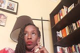 Black Woman wearing red dress near a book shelf