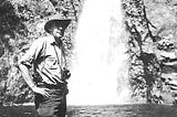Howard Zahniser, who wrote the first draft of the Wilderness Act in 1956, standing next to a waterfall.