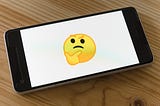 A cell phone with a white screen and an emoji. It represents “I wonder…” with an eyebrow raised and a finger on the chin.