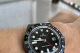 A black Q Timex watch on a wrist.