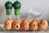 A set of eggs with drawn faces — some happy, some sad, some scared