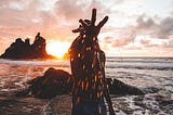 Guy in the sunset at a beach, splashing water at a camera.