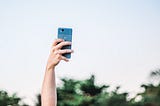 A hand holding a smartphone in the air
